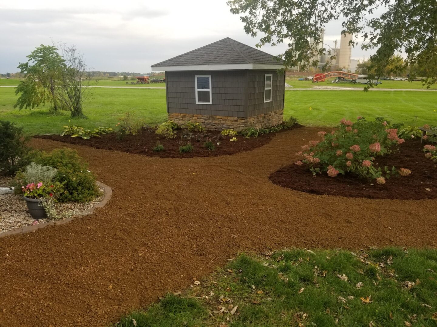 Brown shed with landscaping and gravel path.